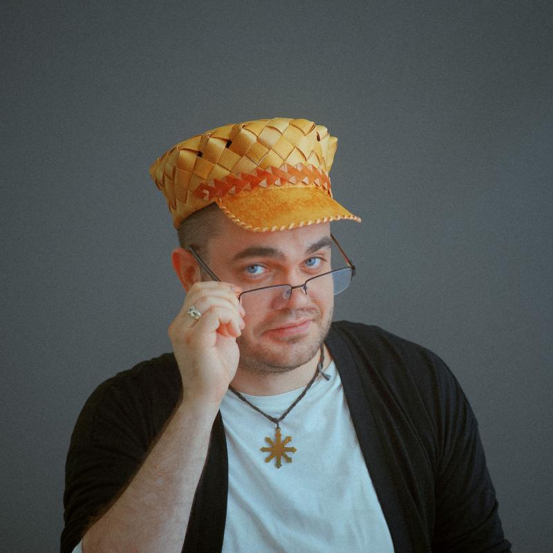 Anna wearing a traditional handcrafted birch bark hat. Looking at the camera with a hint of a bemused smirk.